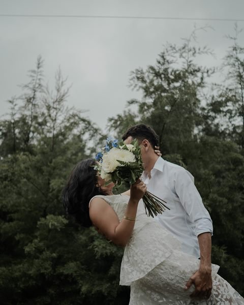 Pareja entre pinos con un ramo de flores